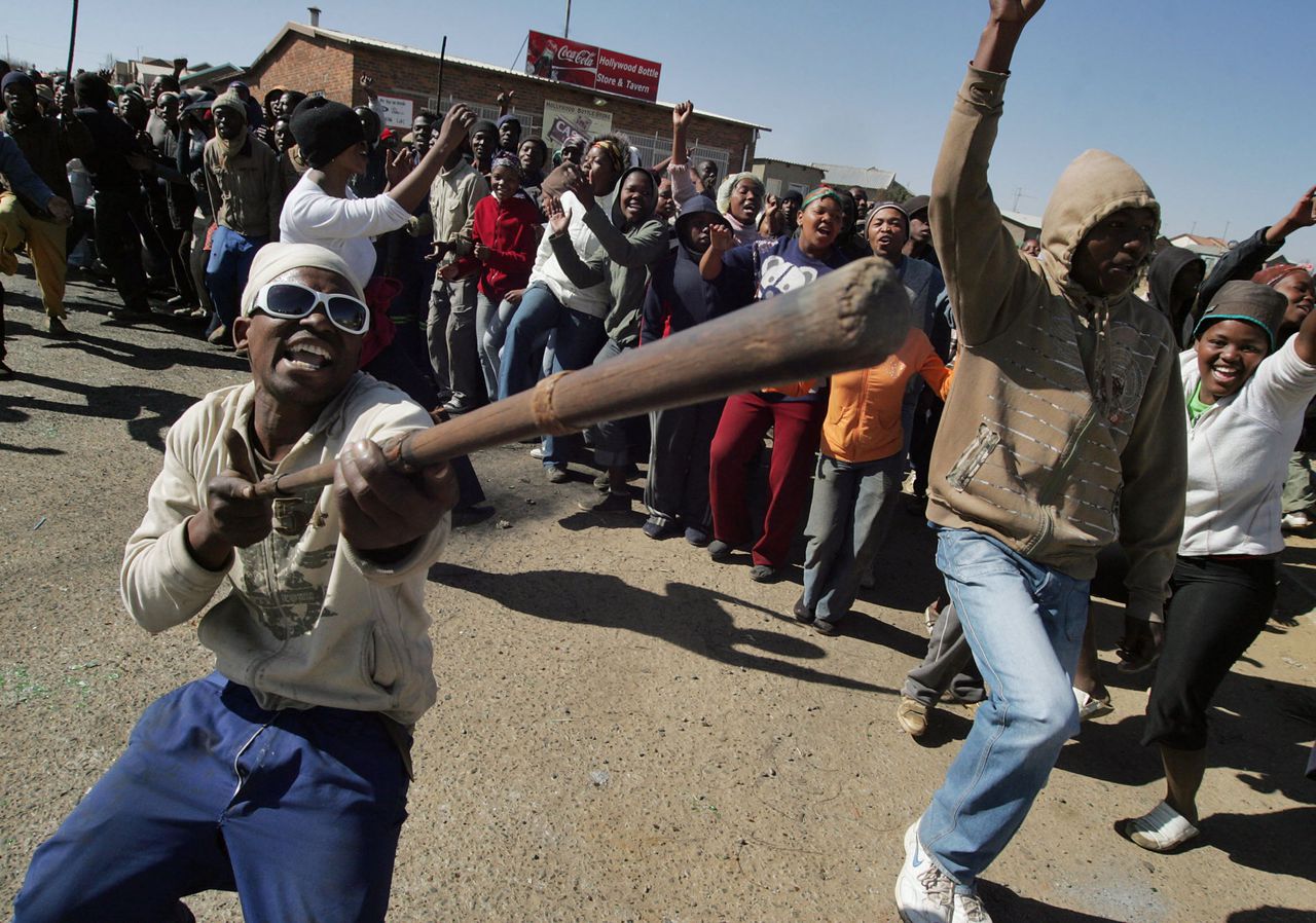 Inwoners van de Zuid-Afrikaanse township Siyathemba zingen protestliederen tijdens een demonstratie voor betere publieke dienstverlening. In vier dagen tijd zijn in de township meer dan 100 mensen gearresteerd. Velen raakten gewond. De nieuwe regering van president Zuma dreigde gisteren harder op te treden. De rellen volgen op stakingen van Zuid-Afrikaanse arbeiders voor loonsverhoging. (Foto AFP) Residents from Siyathemba township in Balfour, in Mpumalanga region, chant revolutionary songs on July 23, 2009 during their protest march against service delivery in their area. Its been four days since the township erupted in flames, more than 100 people have been arrested and many more injured. Violent demonstrations against shoddy public services spread across townships in South Africa, as President Jacob Zuma's new government, today, warned protesters they must respect the law. AFP PHOTO/ PABALLO THEKISO