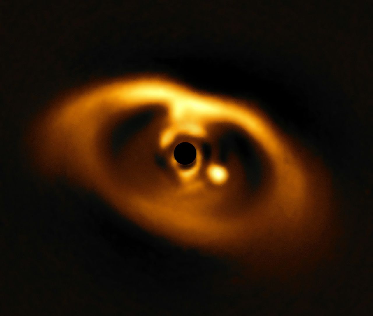 Infraroodfoto van de (afgedekte) jonge ster PDS 70, het gas en stof eromheen én de planeet-in-wording PDS 70b - de lichtvlek rechts ondernaast de (afgedekte) ster. De planeet is bezig om het centrale deel van de schijf van gas en stof rond zijn moederster schoon te vegen.