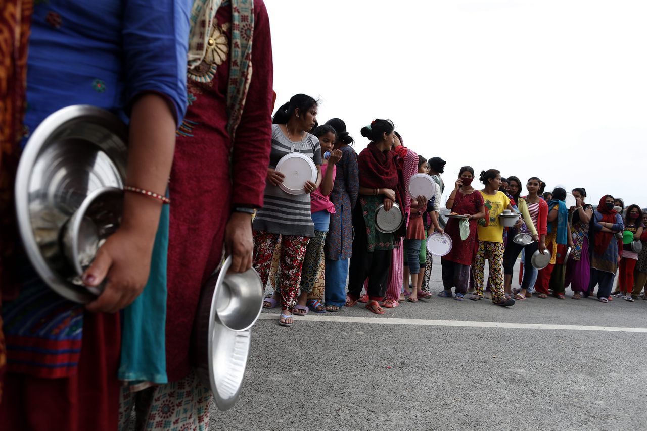 Overlevenden van de aardbeving Nepal staan in de rij voor voedsel.