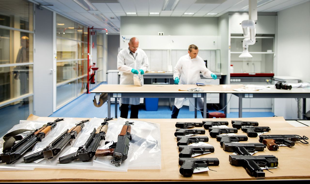 Pistolen, revolvers, automatische wapens, munitie en handgranaten liggen uitgespreid op een tafel in het kantoor van Korps Landelijke Politiediensten. De wapens werden in 2015 aangetroffen in een opslagruimte in Nieuwegein.