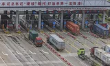 Vrachtwagens rijden door de hoofdingang van de Chinese havenstad Ningbo. EPA/Alex Plavevski. Door de handelstarievenoorlog met de VS is de export vanuit de Chinese kustregio dit jaar gedaald. Foto Alex Plavevski/EPA