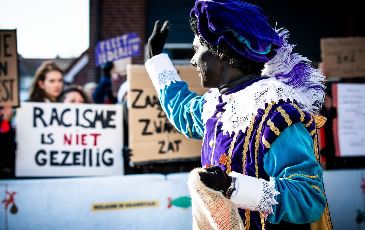 Demonstranten en een Zwarte Piet tijdens de landelijke intocht van Sinterklaas in de Zaanse Schans.