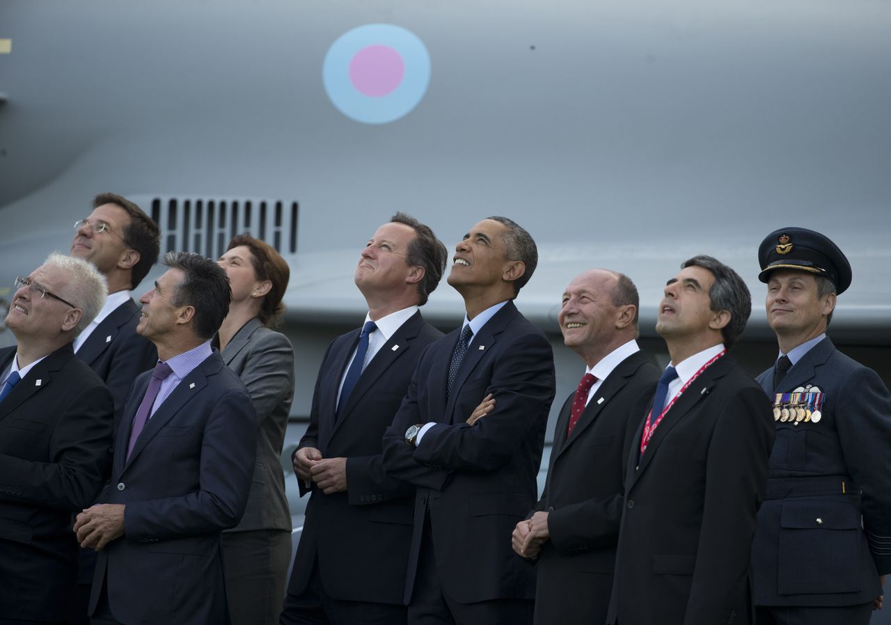 Wereldleiders tijdens de NAVO-top in Wales kijken op naar een vliegtuig dat overvliegt.