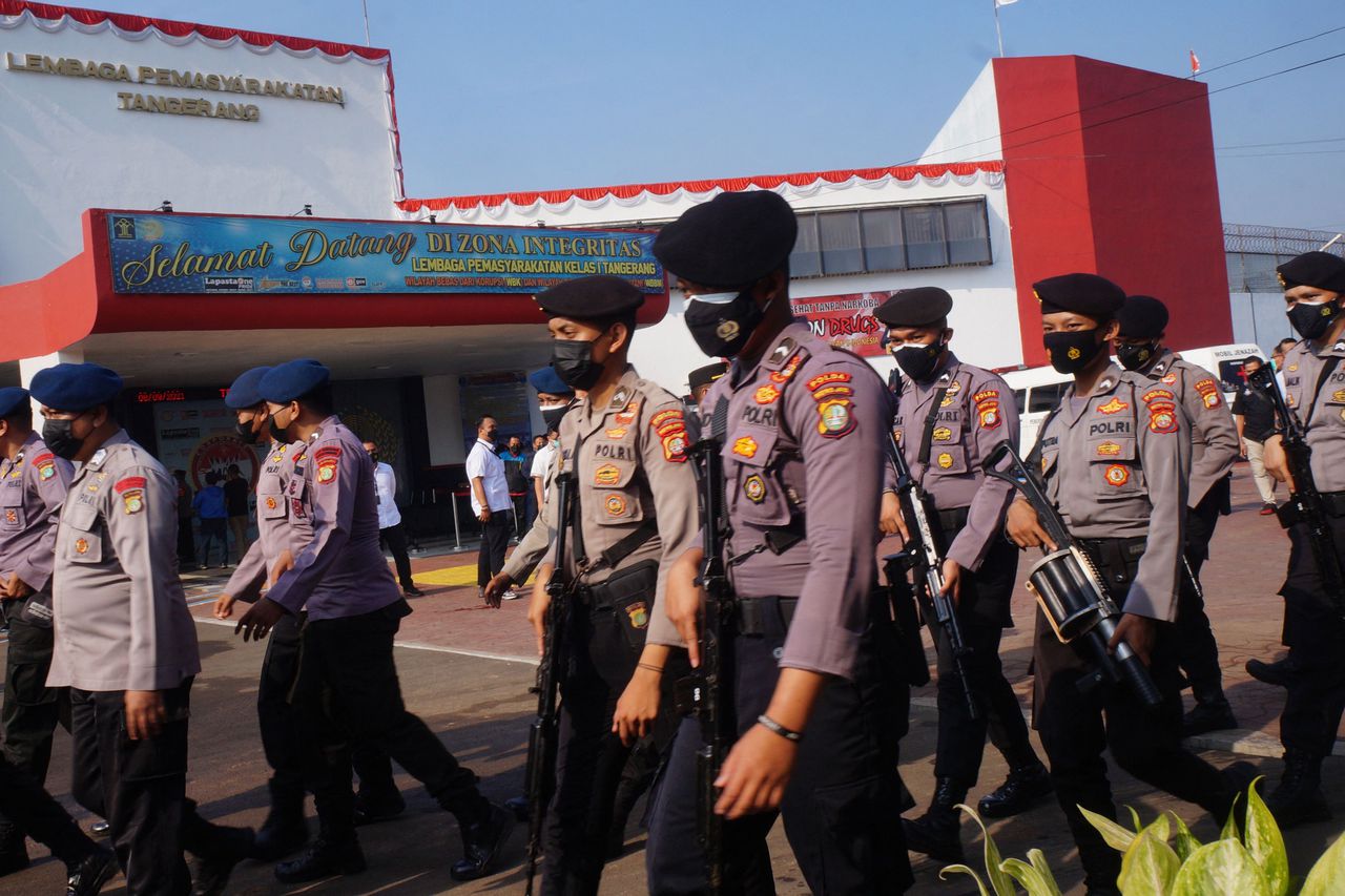 Indonesische politieagenten lopen rond de gevangenis na de brand.