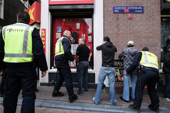 De politie fouilleert voetbalsupporters in Amsterdam.