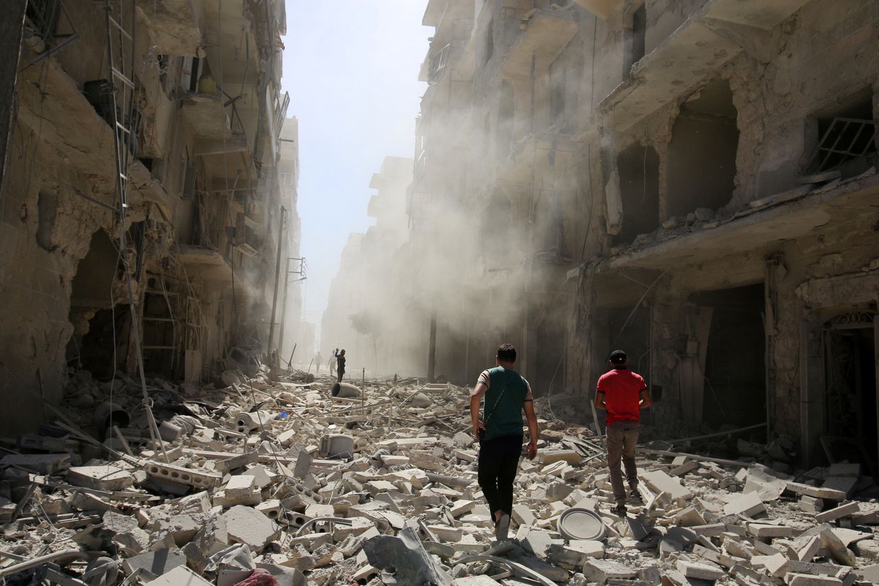 Mannen doorzoeken het puin na een bombardement op Aleppo.
