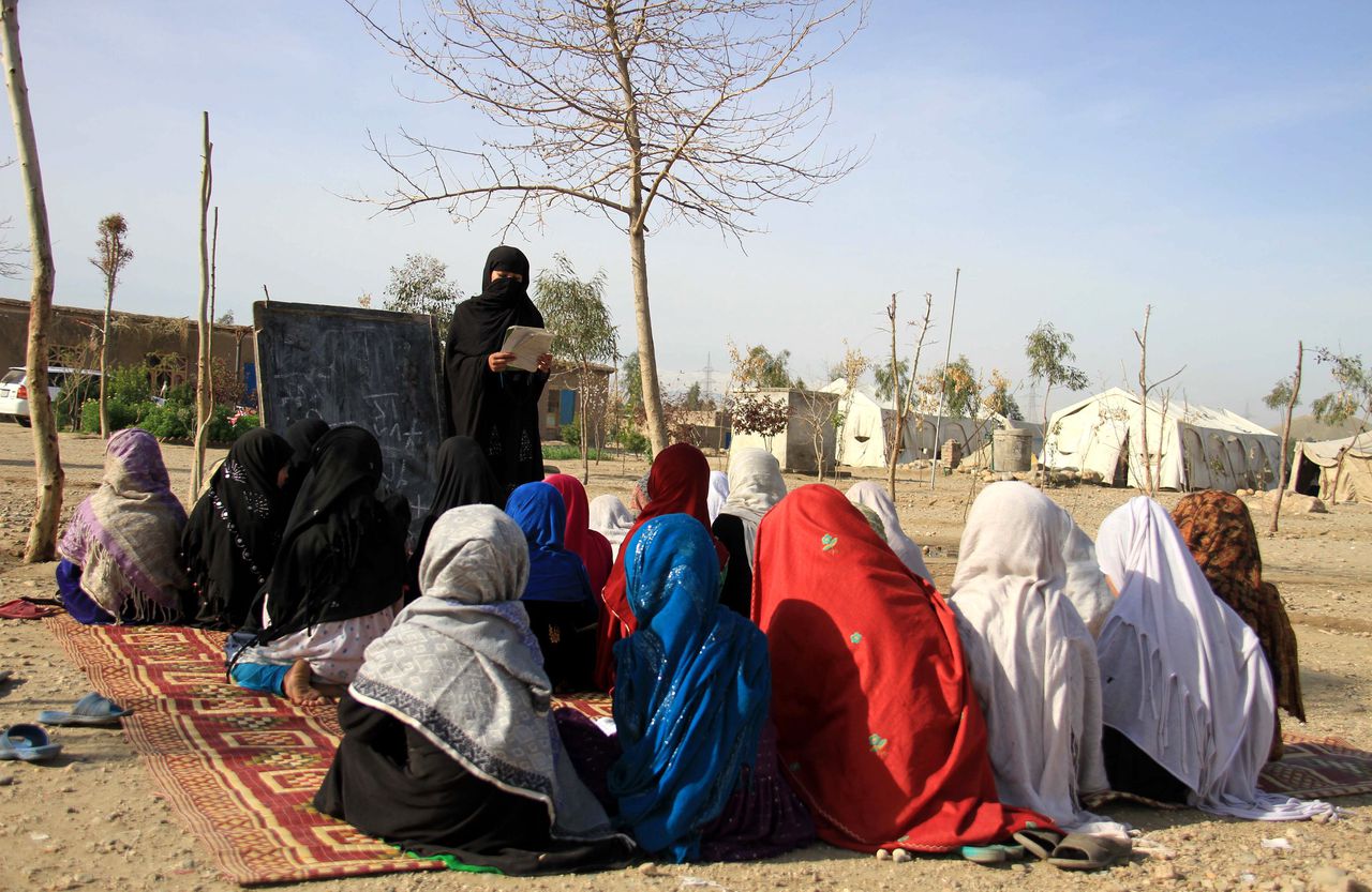 Afghaanse meisjes volgen school in een kamp, door een gebrek aan fatsoenlijke schoolgebouwen.