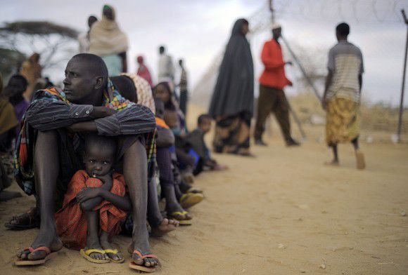 A Somali father with his daughter sits at the head of a queue wuith other refugees at a registration centre on August 2, 2011 at Dagahaley refugee site within the Dadaab complex after having been displaced from their home in southern Somalia by a famine that is ravaging the horn of Africa region. An estimated 3.7 million people in Somalia -- around a third of the population -- are on the brink of starvation and aid agencies are stretched in trying to cope with a daily influx of Somali's escaping not only drought but the al-Shabab extremists who have turned taken advantage of the famine to forcefully arrest and recruit men trying to escape the famine. TOPSHOTS/AFP PHOTO/Tony KARUMBA