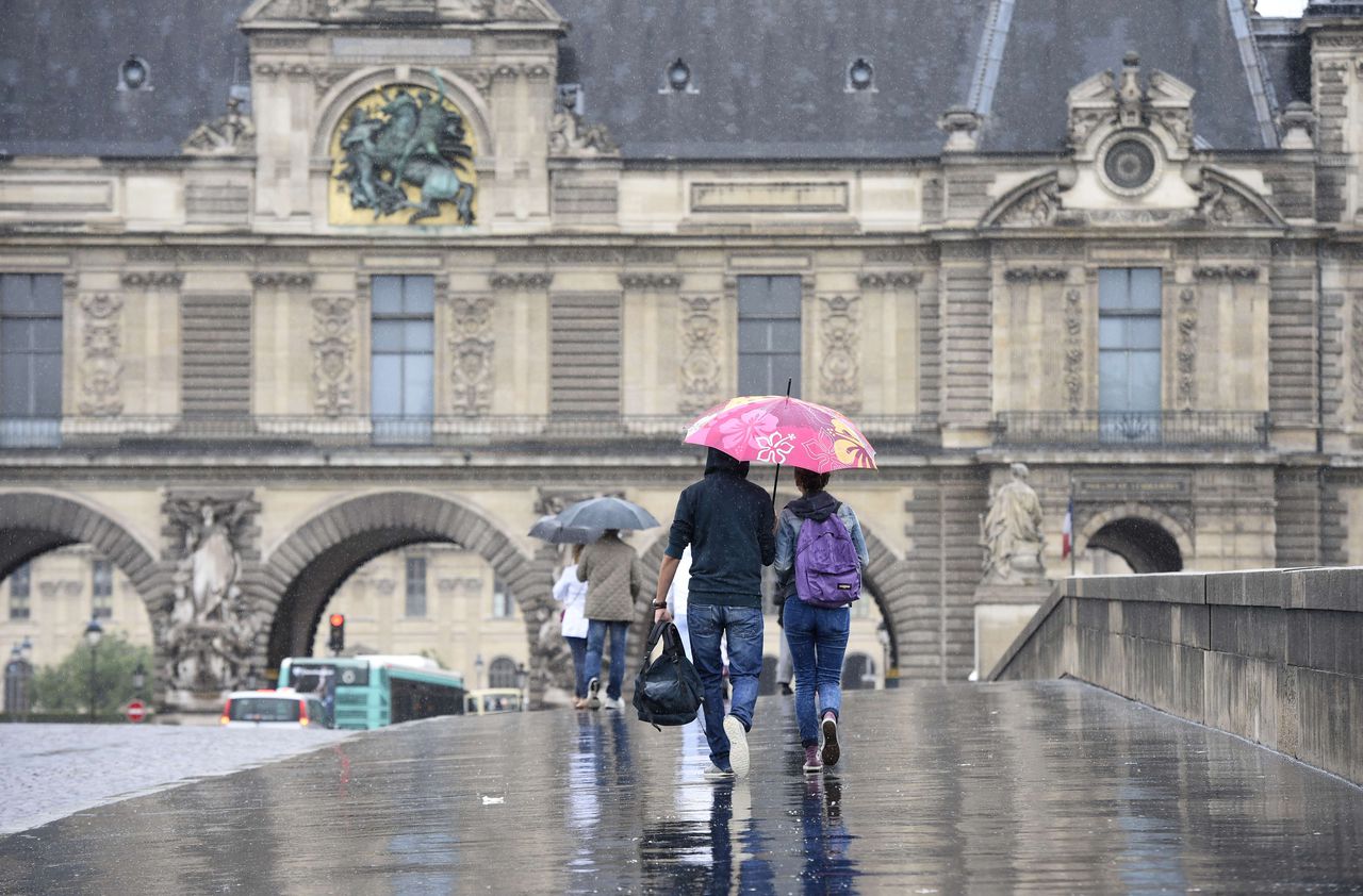 Mensen lopen over een brug nabij het Louvre in Parijs.