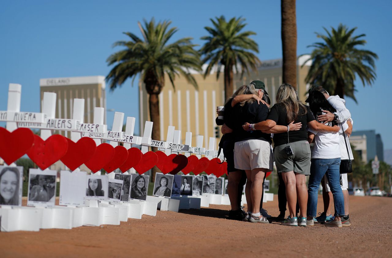 Biddende mensen bij een geïmproviseerd monument voor de slachtoffers van de schietpartij van twee jaar geleden.