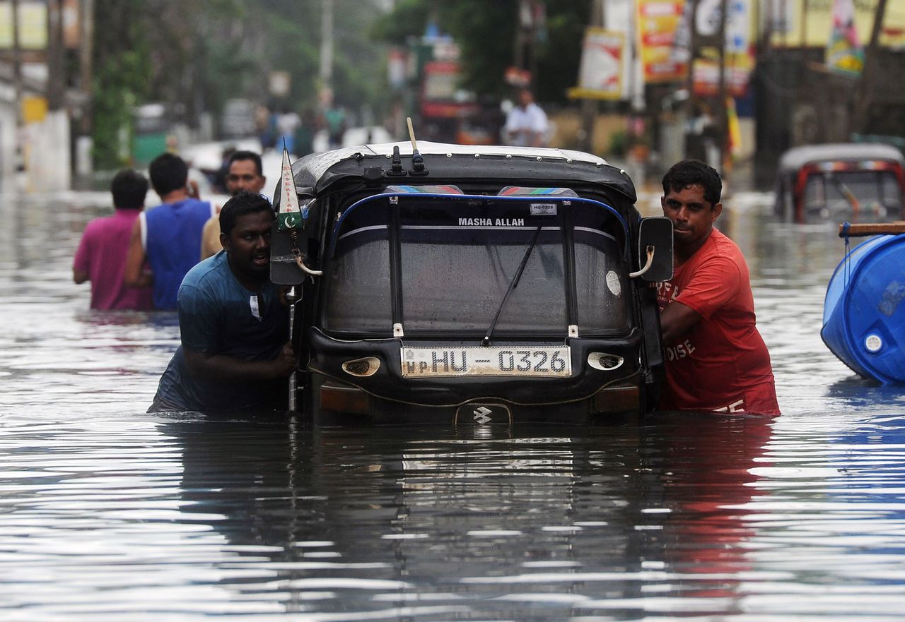 Sri Lankaanse getroffenen duwen een tuktuk door de overstroomde straten.