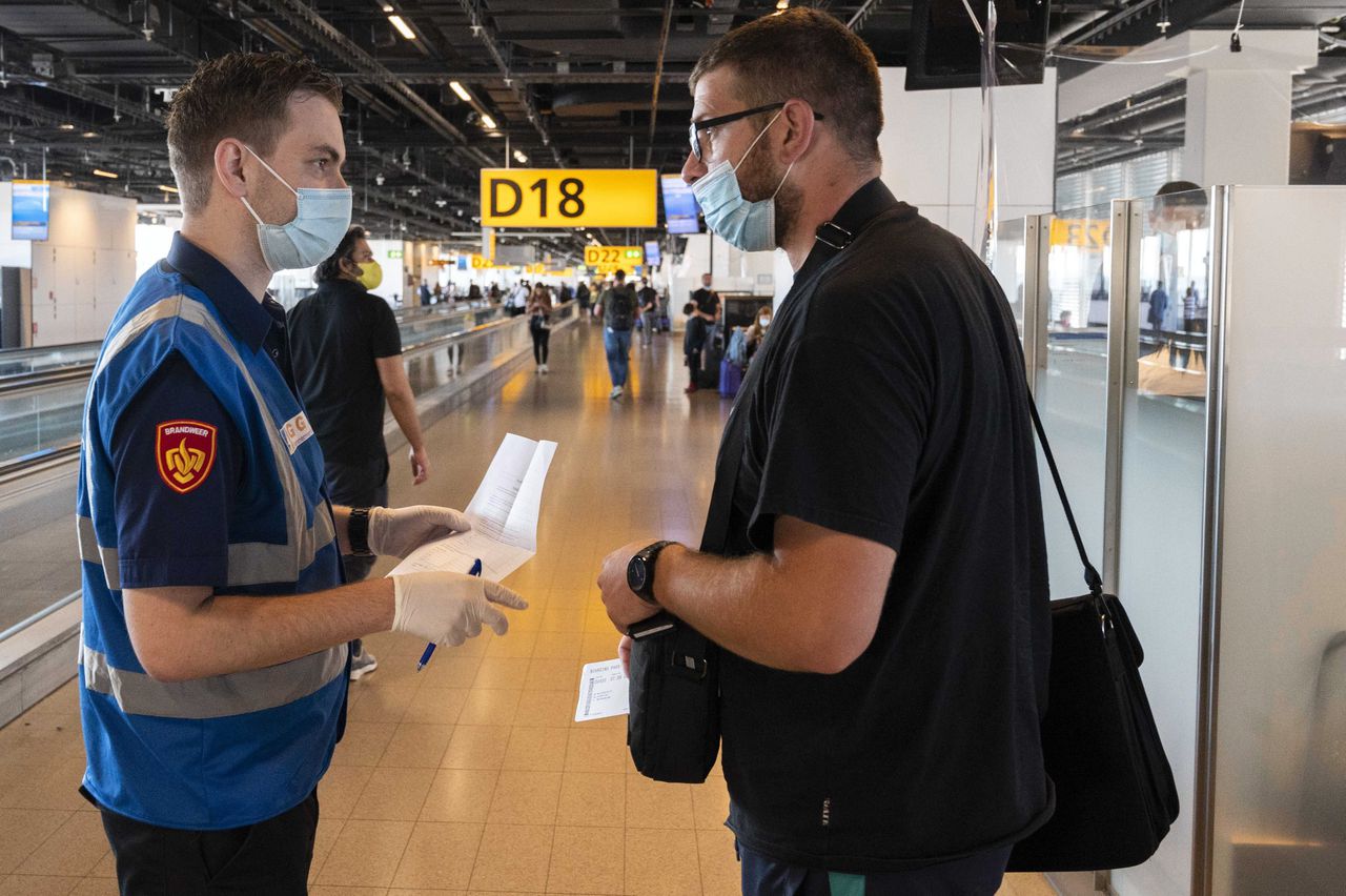 Medewerkers van de GGD ondervragen reizigers op luchthaven Schiphol.
