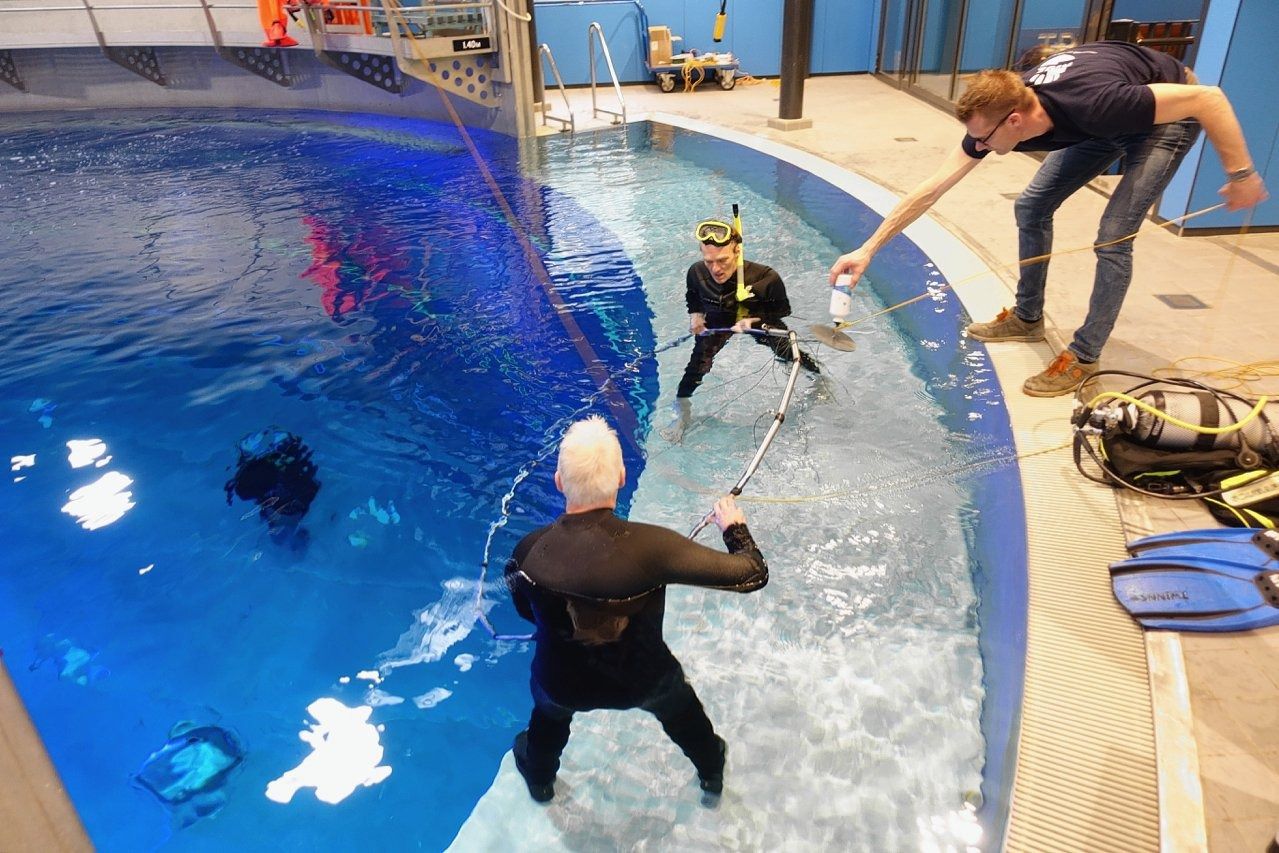 Hans van Haren (in duikpak met snorkel) test een schaalmodel voor zijn onderwatergolvenonderzoek.