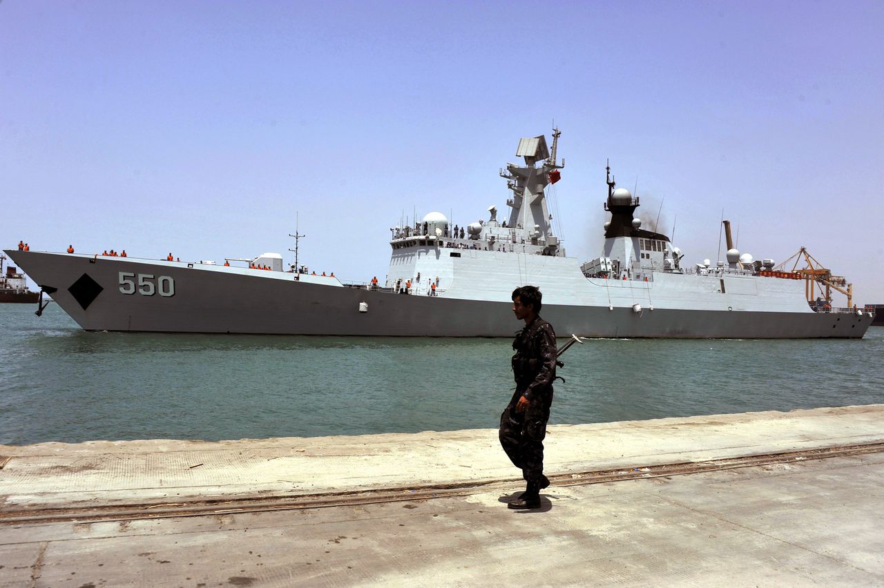 Een Jemenitische soldaat houdt de wacht terwijl een fregat van de Chinese marine de haven van Hodeidah verlaat. Vandaag werden Chinezen uit verschillende belaagde steden geëvacueerd.