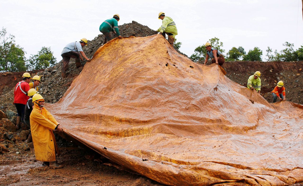Mijnwerkers in het zuiden van de Filippijnen dekken een berg nikkel af met zeil.