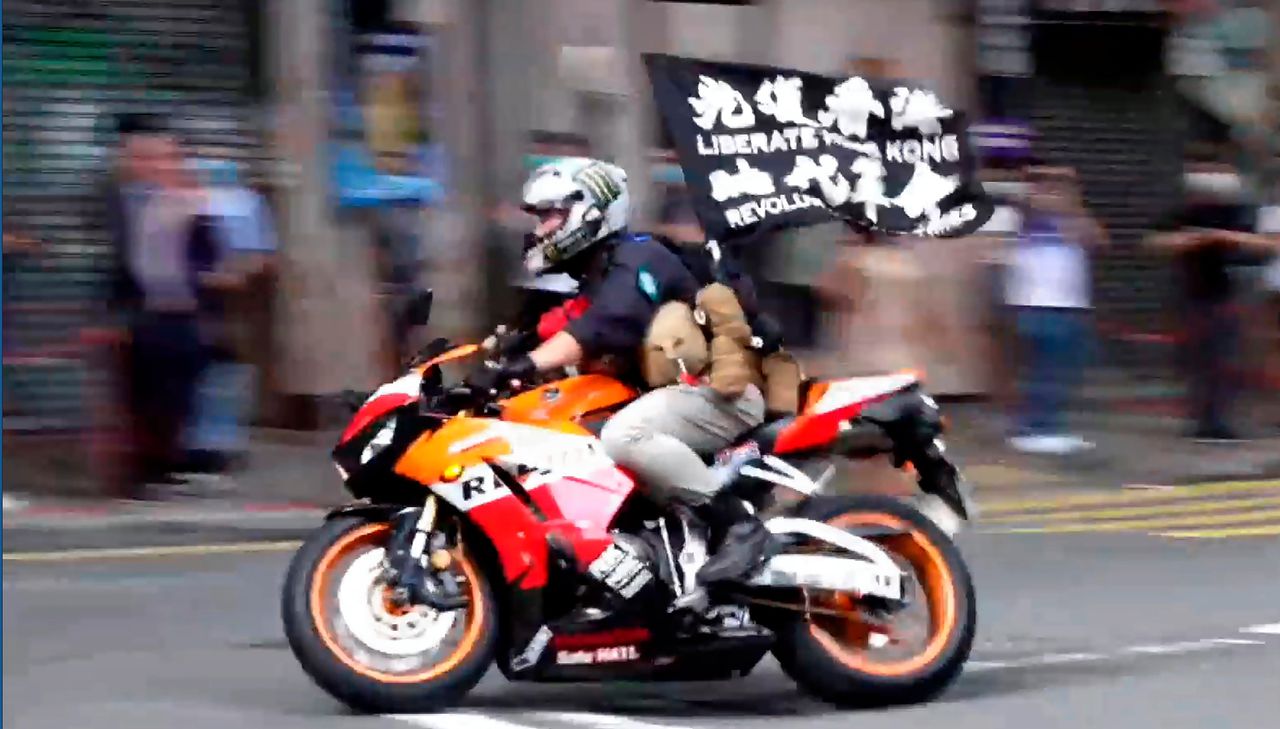 Tong Ying-kit op zijn motor op 1 juli 2020, met de vlag waarop „Bevrijd Hongkong" staat.