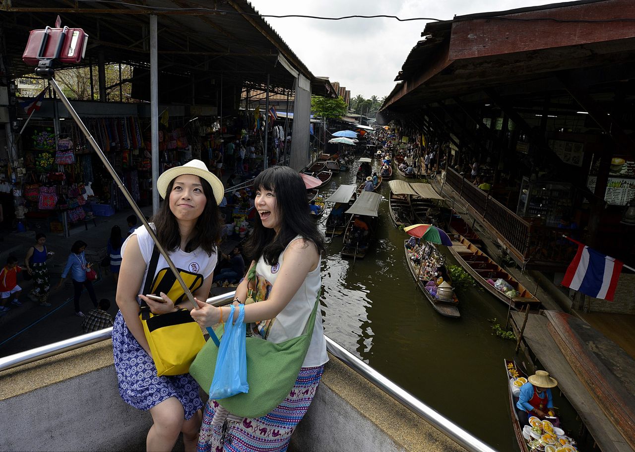 Aziatische toeristen in Thailand poseren voor een selfiestick.