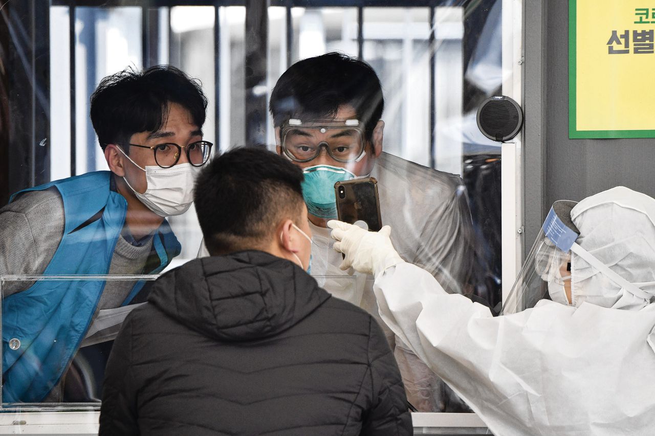 Ambtenaren controleren de informatie van een bezoeker voor de Covid-19-test in een doorloopteststation in het Jamsil Sports Complex in Seoul.