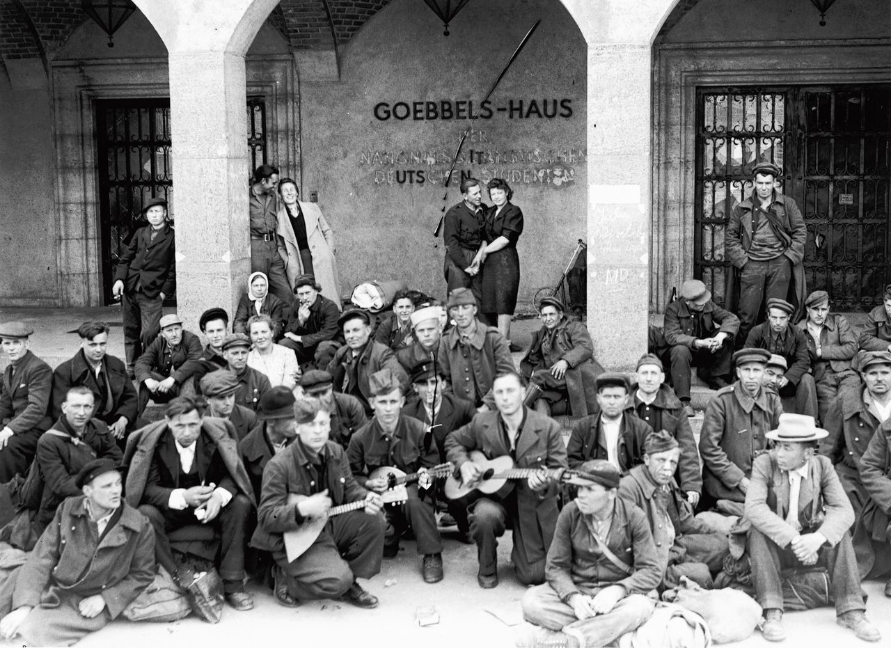A group of Russian slave workers liberated by the US 7th Army in Wurzburg, July 1945. They are sitting outside the Goebbels House, a propaganda training college. (Photo by Horace Abrahams/Keystone/Hulton Archive/Getty Images)