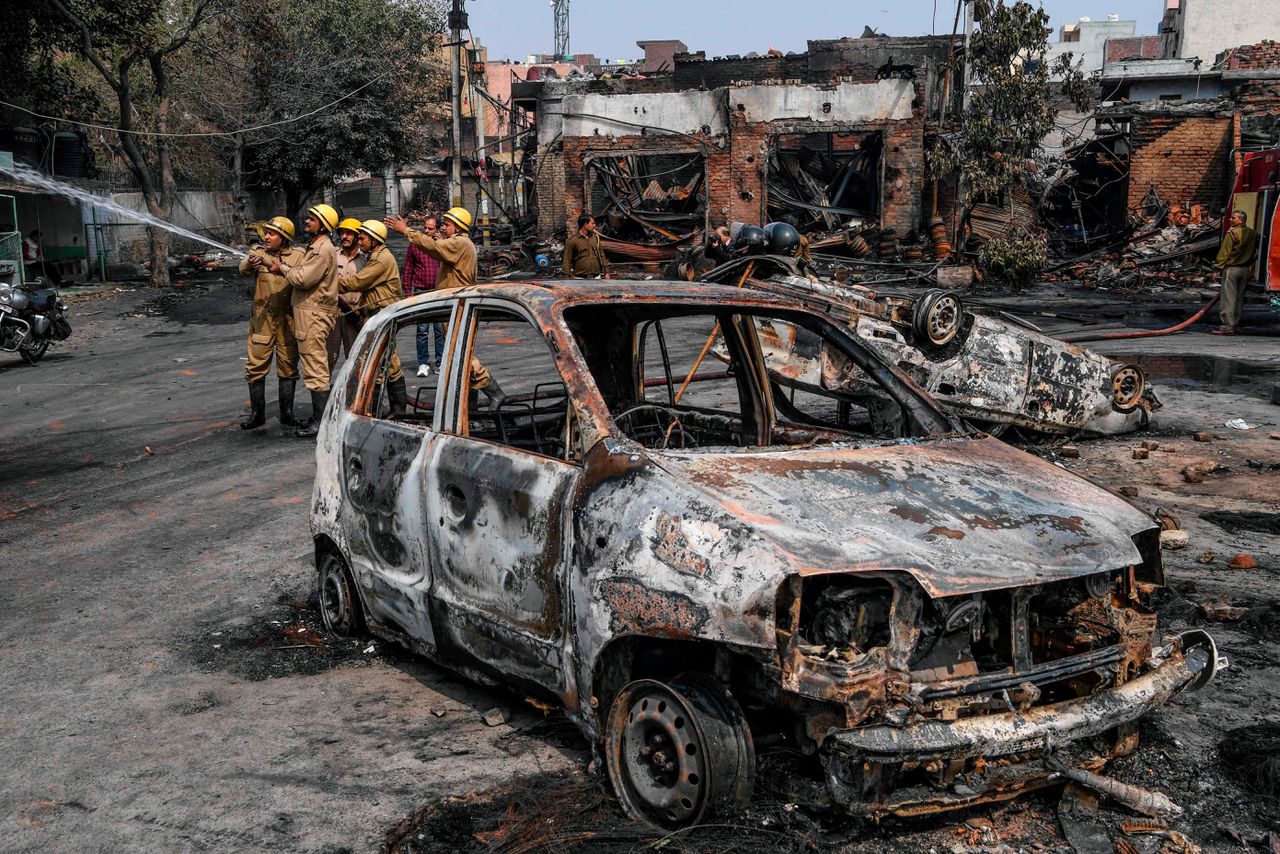 Een uitgebrande auto tijdens rellen in de Indiase hoofdstad New Delhi.