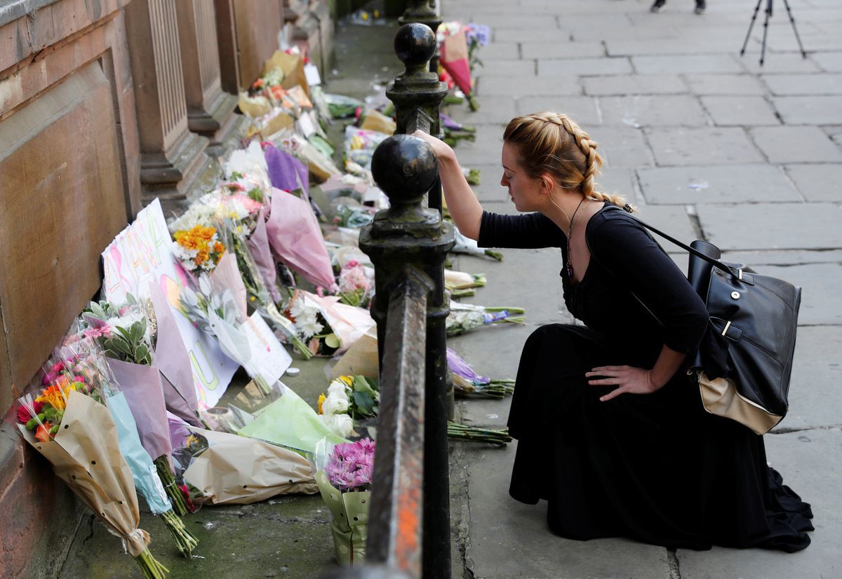 Een vrouw knielt voor een zee aan bloemen voor de slachtoffers van de aanslag in Manchester.