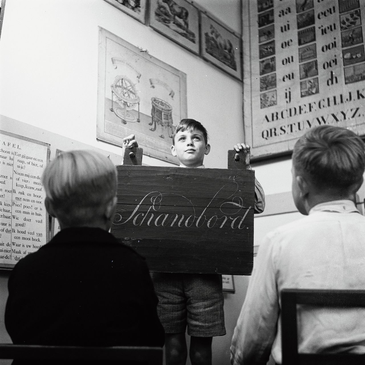Ongedateerde foto van een leerling met zogenoemd ‘schandbord’.