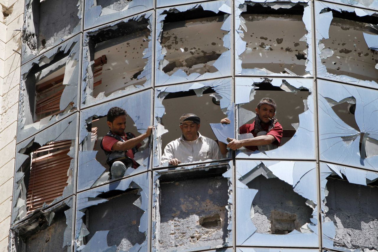 Gebroken glas van een kantoorgebouw dat is beschadigd bij gevechten tussen Houthi's en regeringstroepen in Sanaa vandaag.