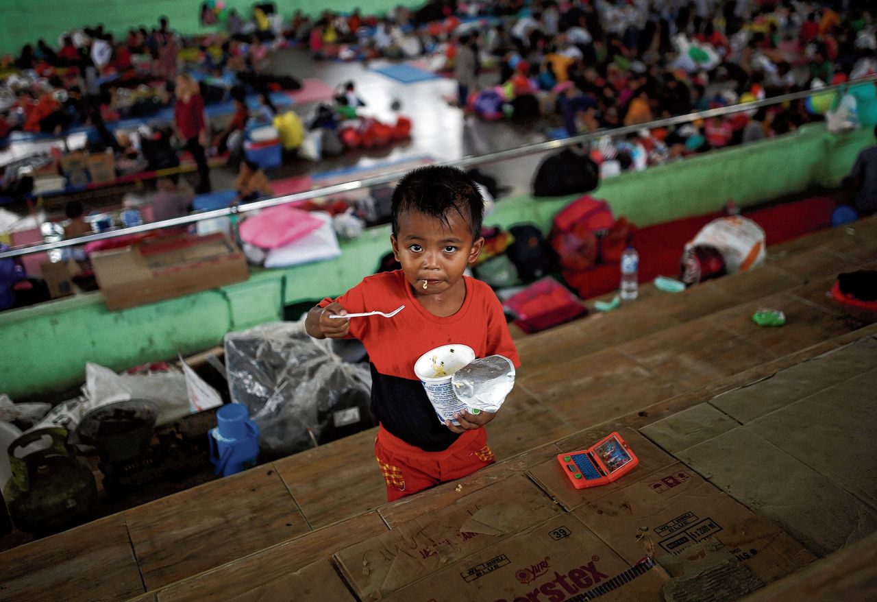 Een geëvacueerd Balinees jongetje eet noedels in een sporthal in Klungkung, waar gevluchte Balinezen worden opgevangen.
