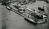 Luchtopname van de terreinen van de Holland-Amerika Lijn en op de voorgrond het kantoorgebouw aan de Wilhelminakade en de Rijnhaven, rechts. Op de achtergrond de Spoorweghaven en links de Nieuwe Maas in 1950