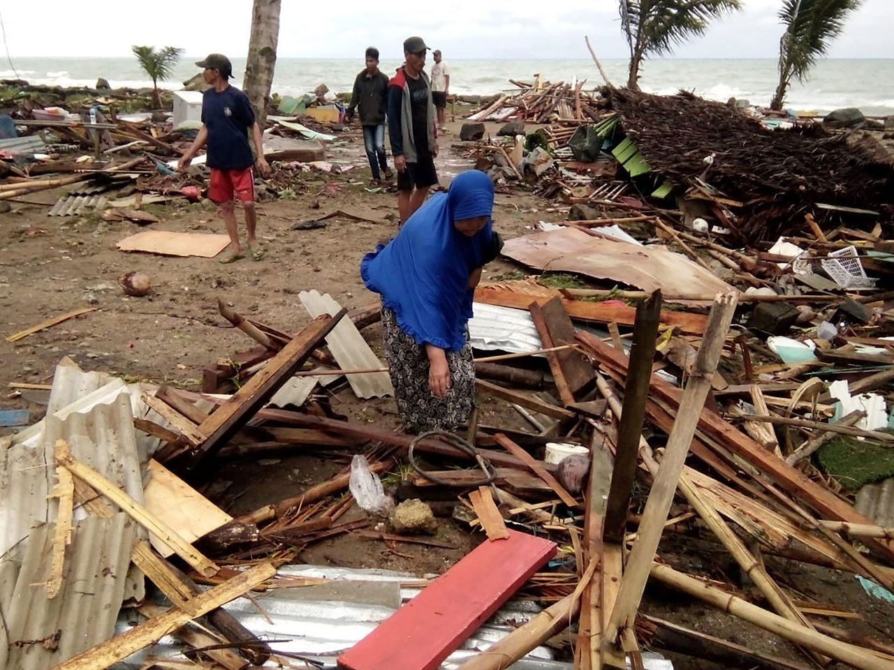 Bewoners bekijken de schade aan hun huizen bij het strand van district Carita, provincie Banten, op de ochtend na de tsunami.