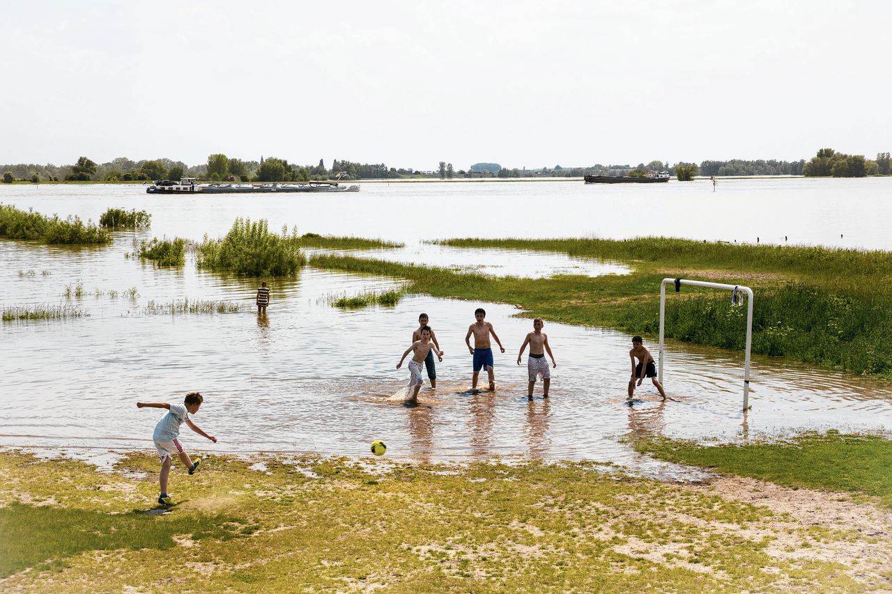 Jongens voetballen in de als gevolg van hoog water ondergelopen uiterwaarden van de Waal bij Ochten.