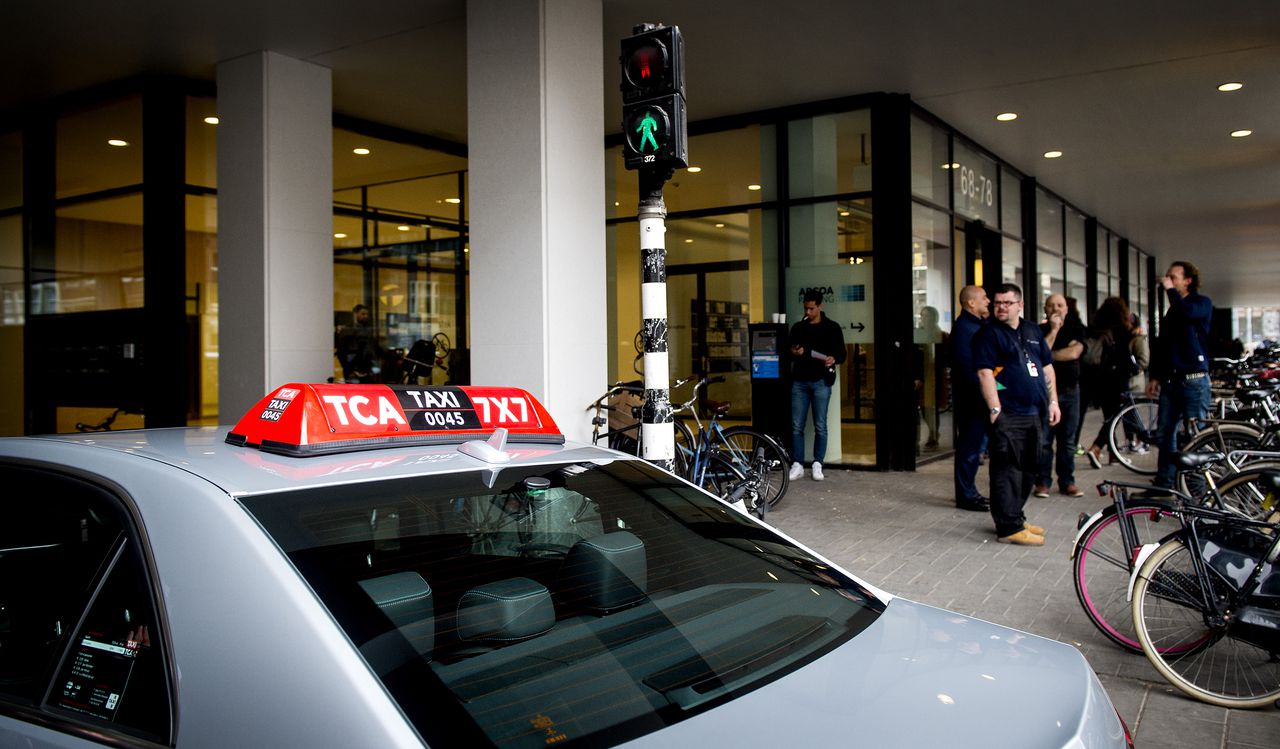 Een gewone taxi rijdt langs het kantoorpand waarin internettaxidienst Uber een ruimte huurt, nadat de Inspectie Leefomgeving en Transport een inval heeft gedaan bij de taxidienst in maart.