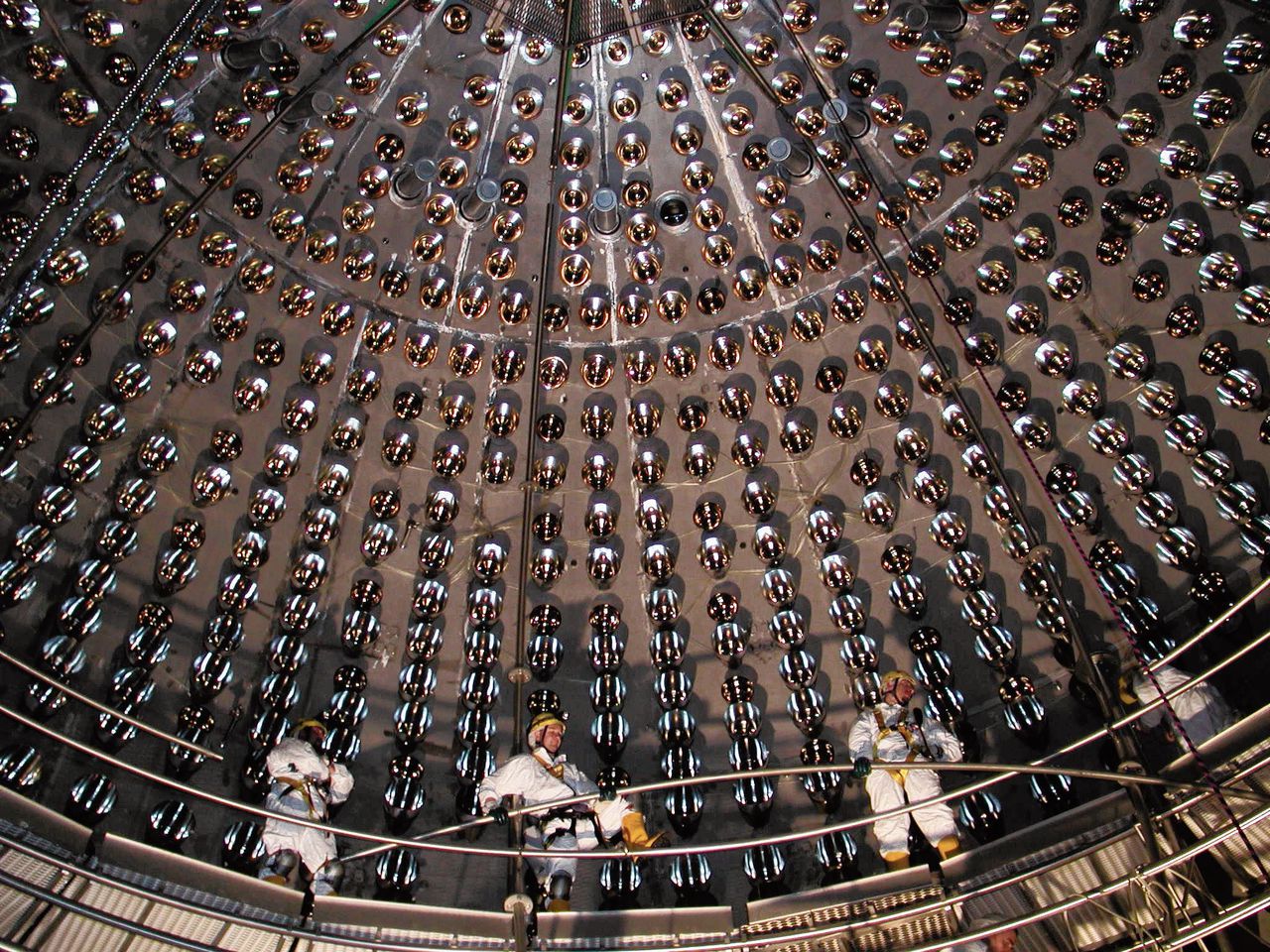 Boven: Twee nylon vaten vol water in de Borexino-detector. Daaronder: medewerkers brengen detectoren aan.