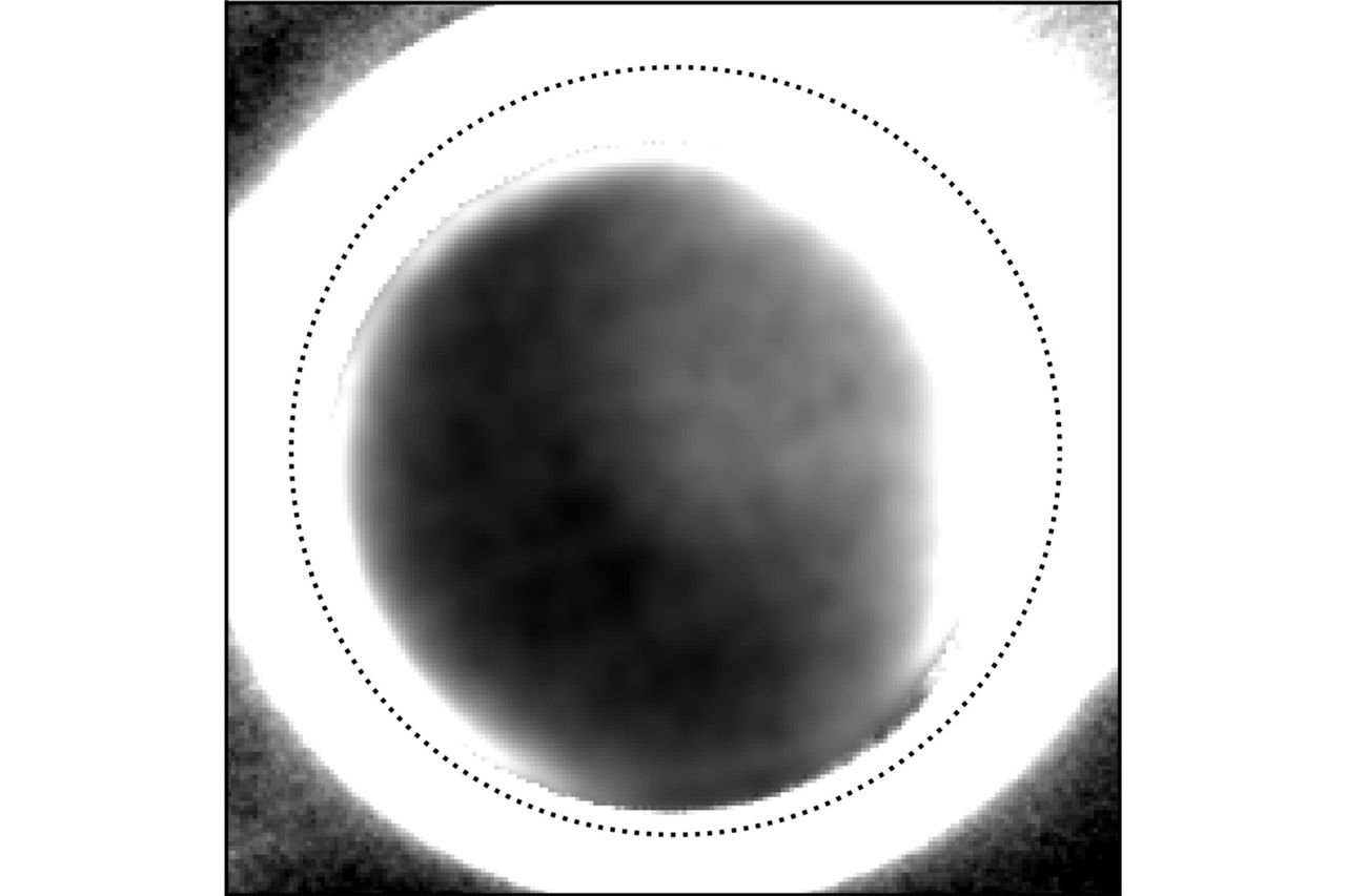 Foto van de donkere kant van Pluto. De stippellijn geeft de rand van de dwergplaneet aan, het felle licht eromheen is afkomstig van de zon. De rechterkant is verlicht door maan Charon. In het midden van Pluto is een duidelijk lichtere vlek te zien, waarschijnlijk doordat daar veel stikstof- en methaanijs is.