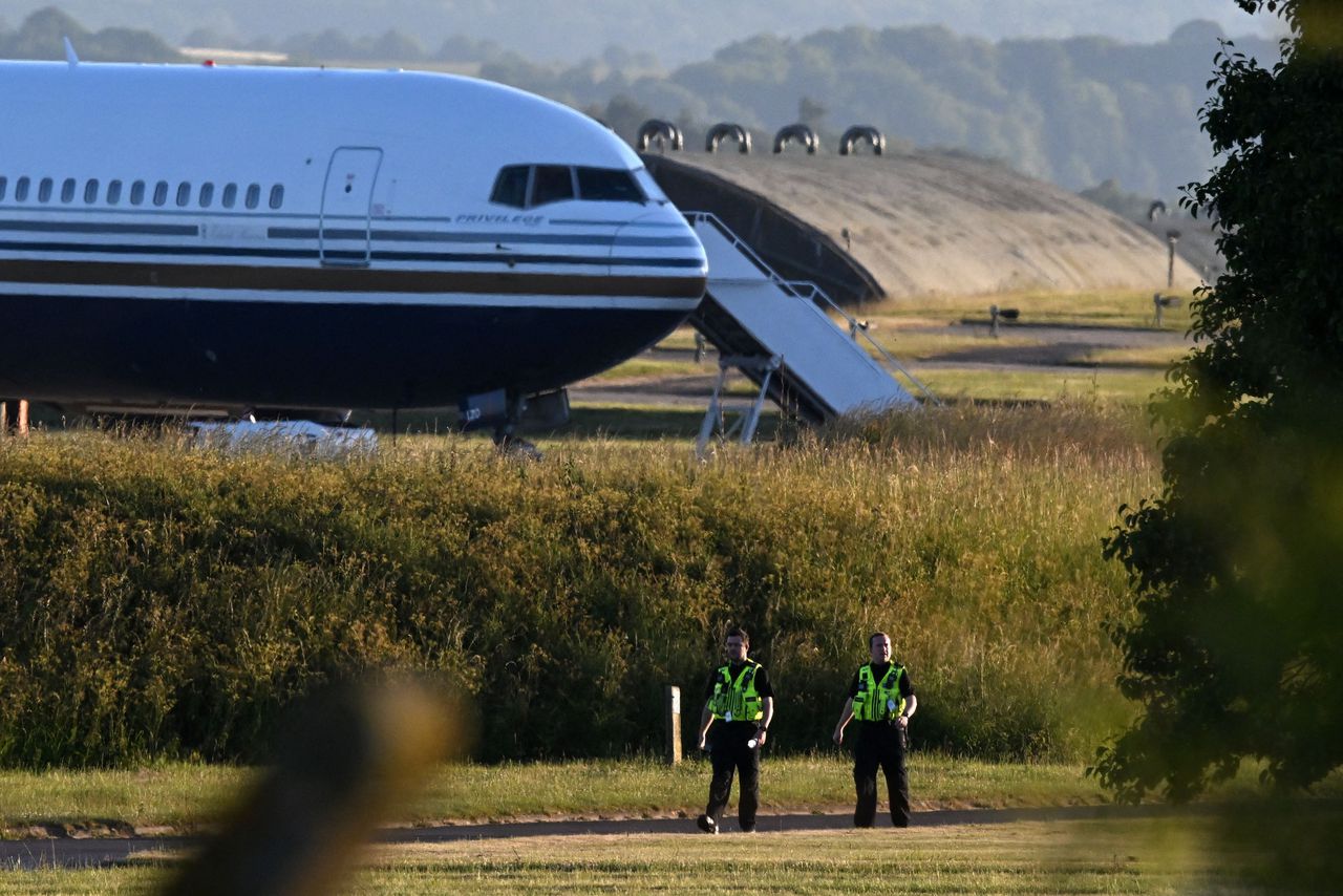 Twee Britse agenten lopen dinsdag bij een militaire basis in het Britse Amesbury langs het vliegtuig dat naar Rwanda zou vliegen met uitgezette asielzoekers aan boord, een vlucht die op het laatste moment werd geblokkeerd door een uitspraak van het Europees Hof voor de Rechten van de Mens.