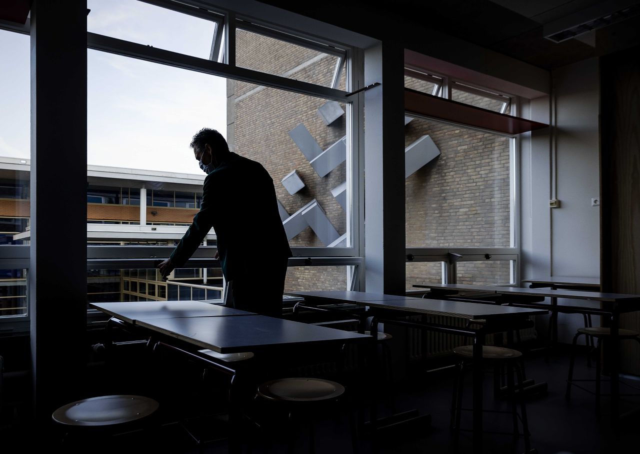 Een leraar zet een raam van een klaslokaal van het Mendel College open, Haarlem.