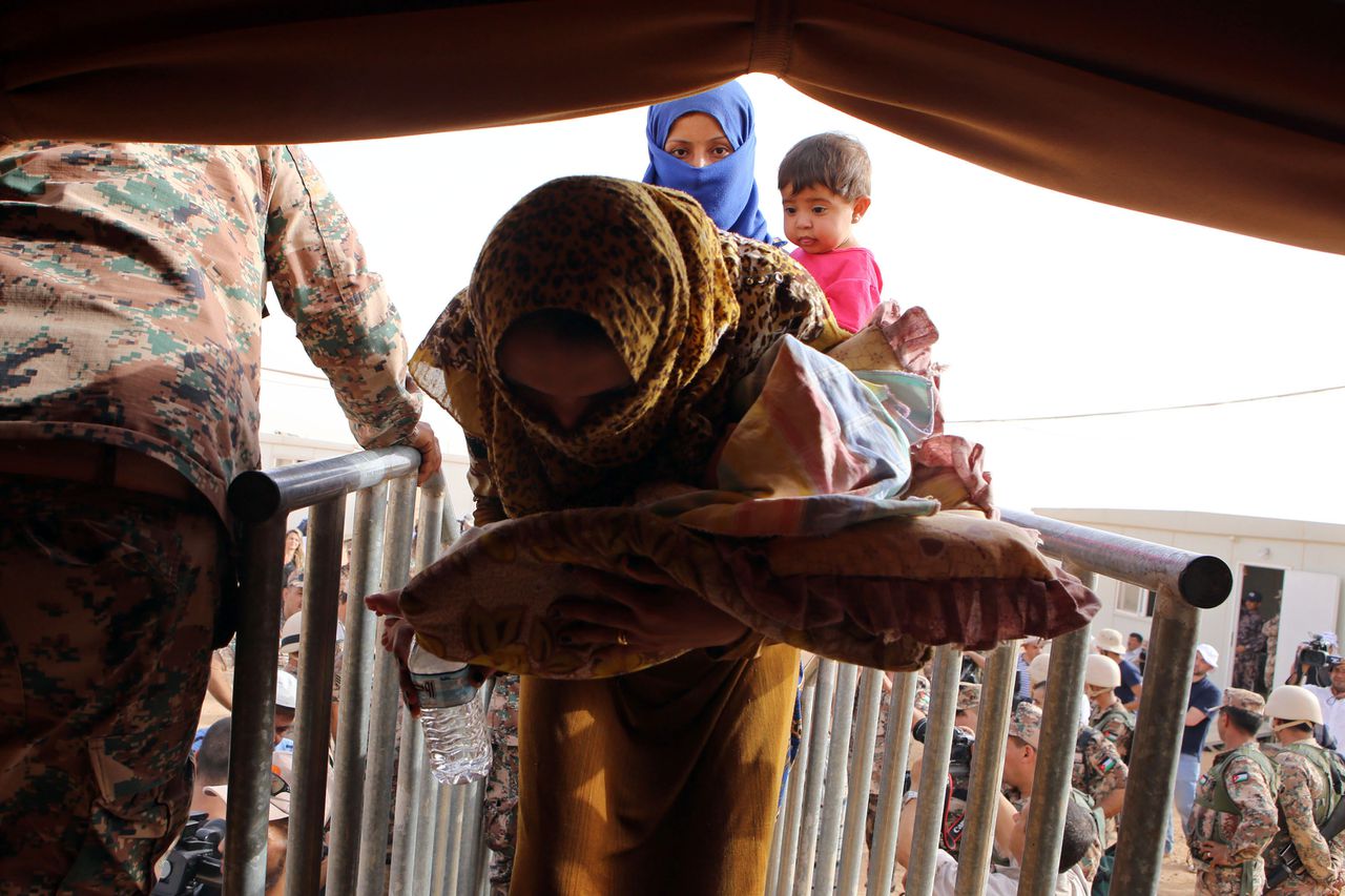 Een Syrische vrouw die de grens met Jordanië heeft weten over te steken, wordt opgevangen door militairen.