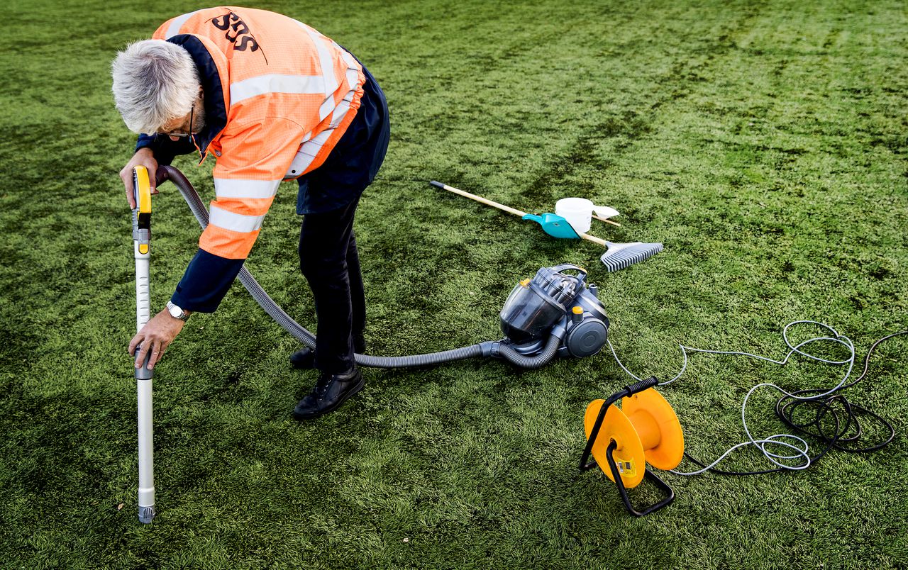 Een medewerker van Vereniging Band en Milieu verzamelt rubberkorrels op een voetbalveld van kunstgras van voetbalvereniging Roda 23 in Amstelveen. De korrels worden op het laboratorium van de brancheorganisatie getest op de aanwezigheid van kankerverwekkende stoffen.
