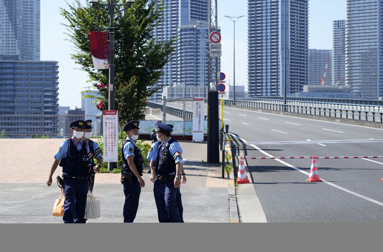 Politiebeambten bij de toegangspoort van het olympisch dorp, waar een eerste coronageval is geconstateerd.