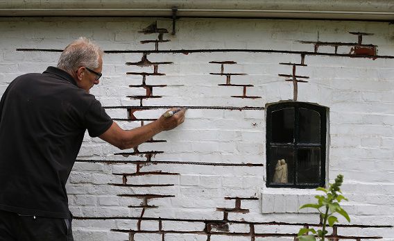 Een inwoner plaatst ijzeren pennen in de oudste woning van Zeerijp.