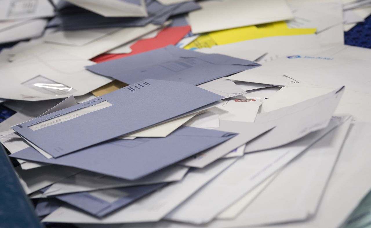 Blauwe enveloppen van de Belastingdienst bij een postsorteermachine van PostNL.