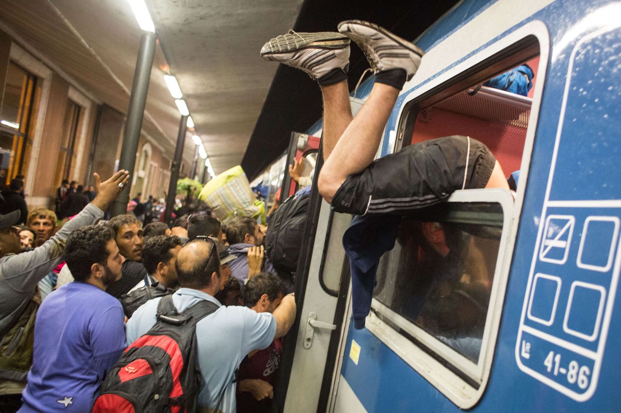 Vluchtelingen proberen een trein in te komen in Hongarije.
