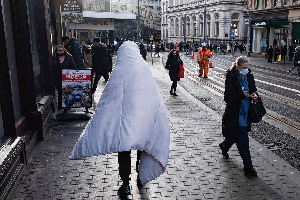 Iemand loopt met een dekbed om zich heen over straat. Steeds meer mensen kunnen vanwege de stijgende energieprijzen en de hoge inflatie niet meer rondkomen.