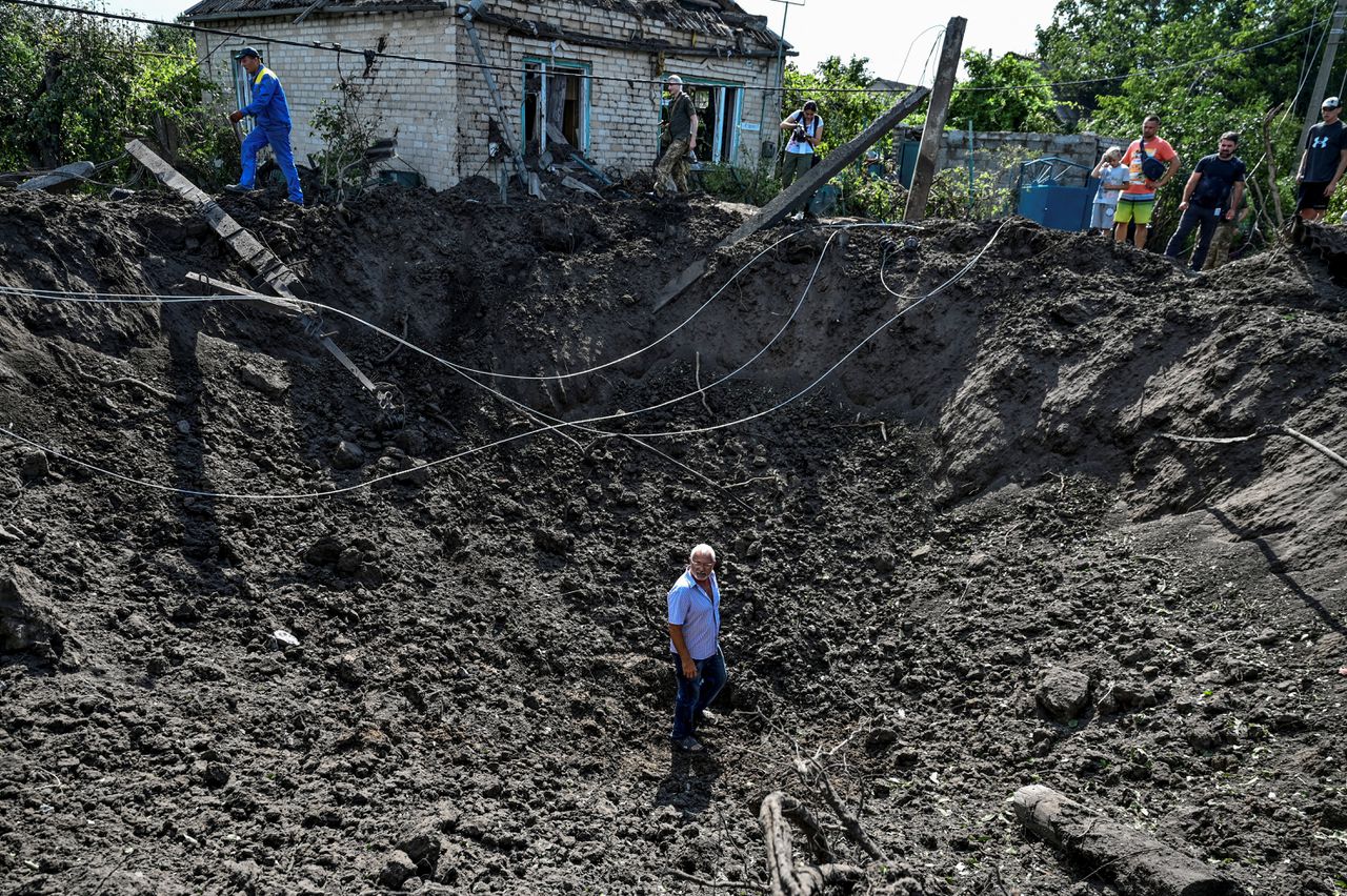 Een man staat in een krater veroorzaakt door een Russische raketaanval in Kushuhum, nabij Zaporizja.