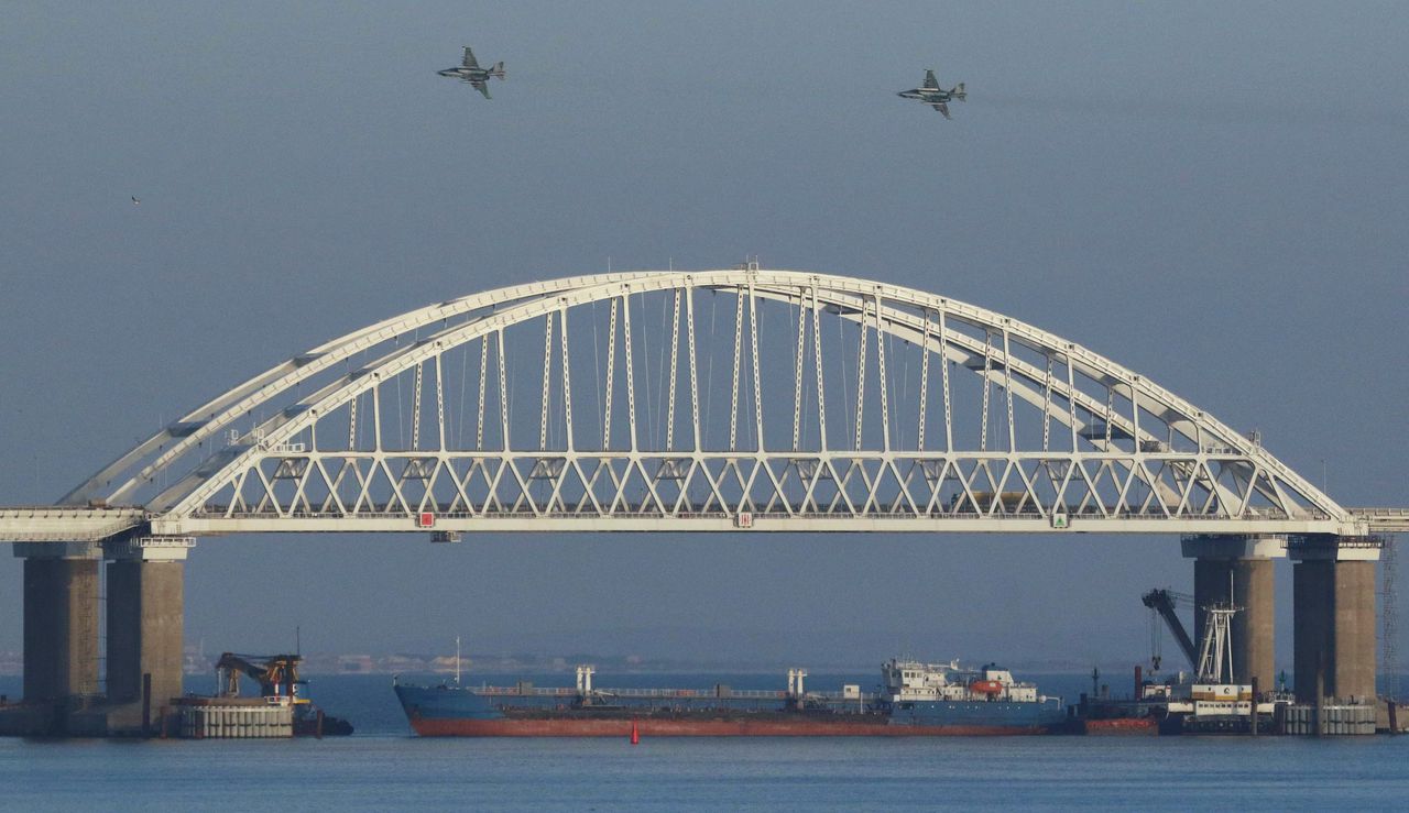 Het vrachtschip blokkeert de ingang van de zee. Boven de Krimbrug vliegen Russische gevechtsvliegtuigen.
