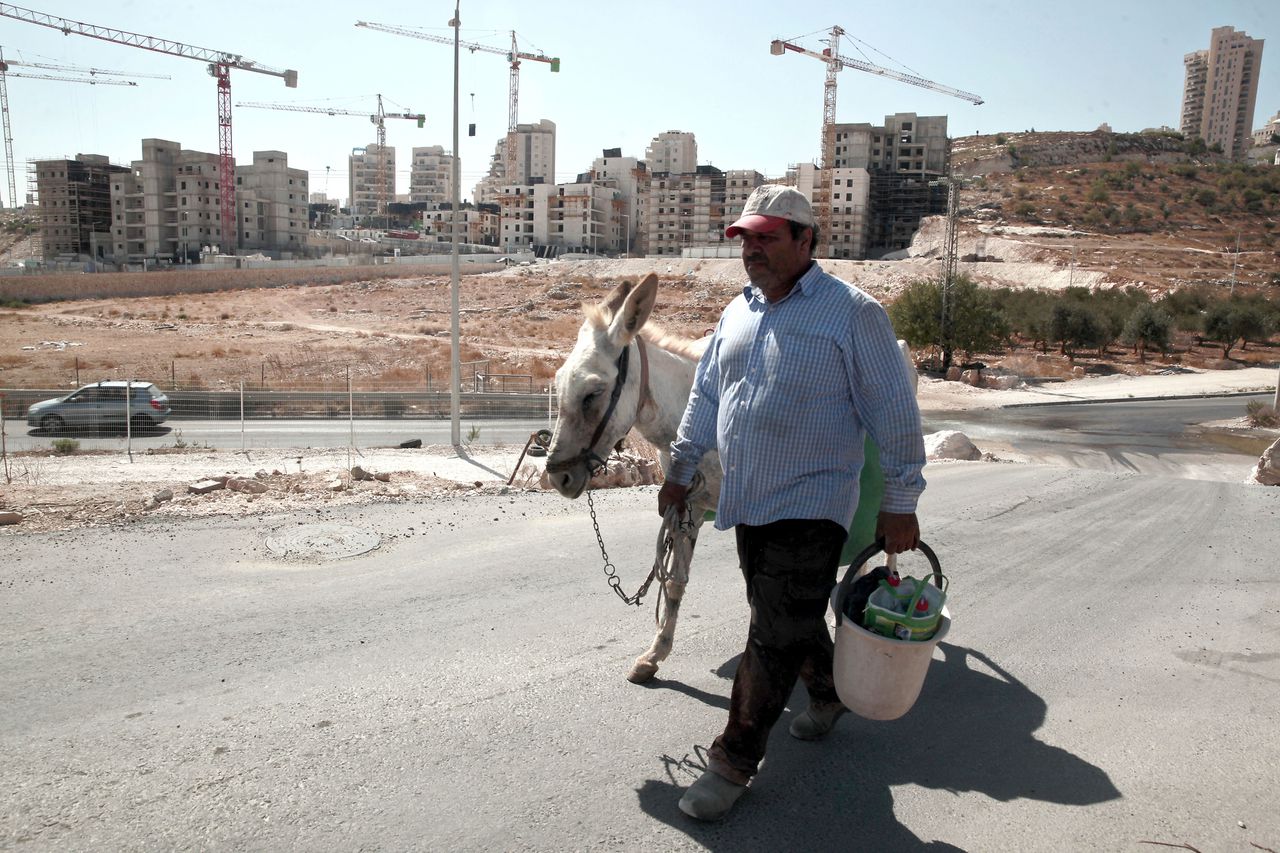 Een Palestijnse man bij een Israëlische nederzetting in bezet Palestijns gebied bij Oost-Jeruzalem. De VN hebben een resolutie aangenomen die de bouw van nederzettingen veroordeelt.