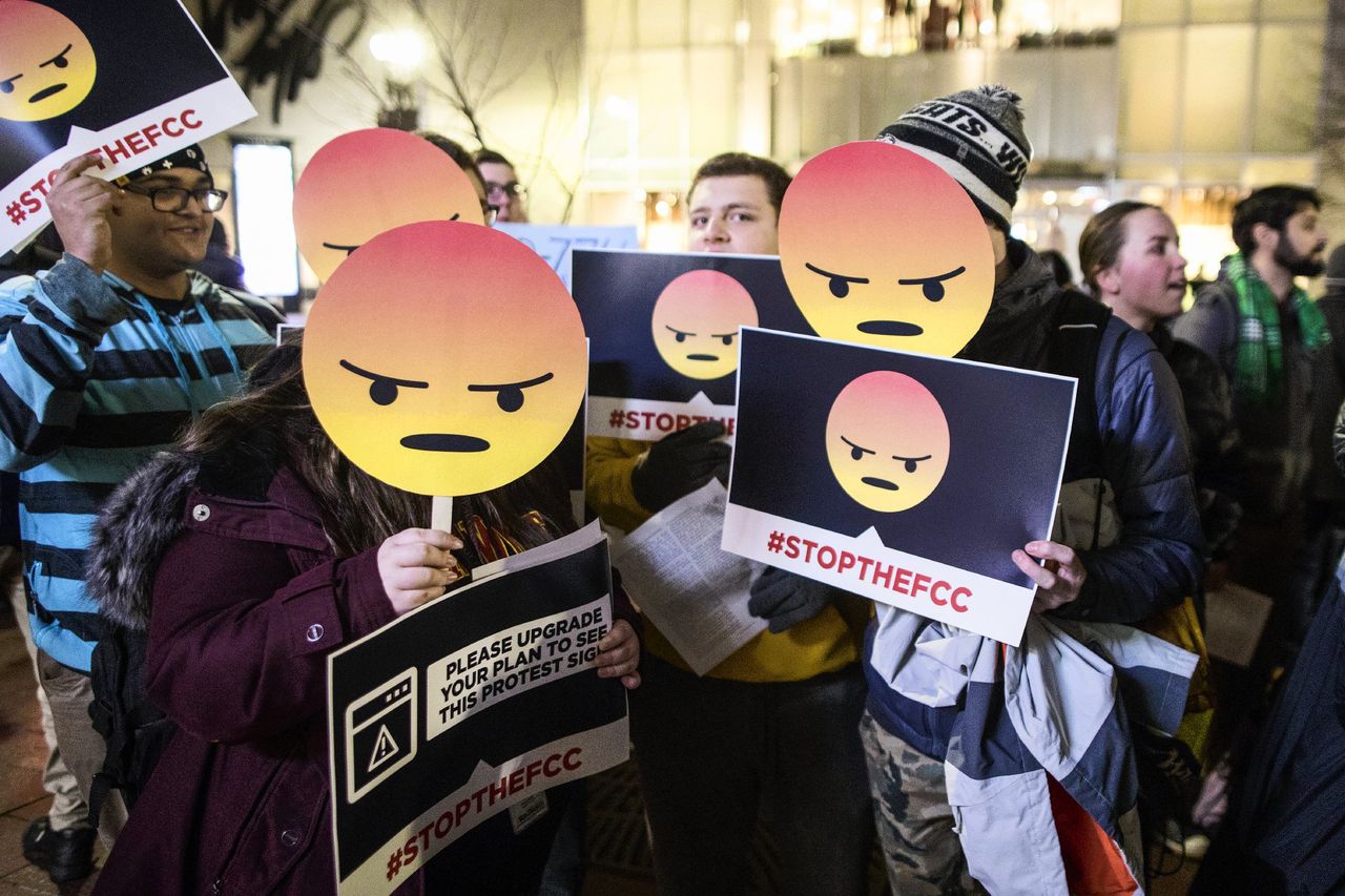 Amerikaanse demonstranten houden borden met boze emoji's op bij een bijeenkomst tegen netneutraliteit.
