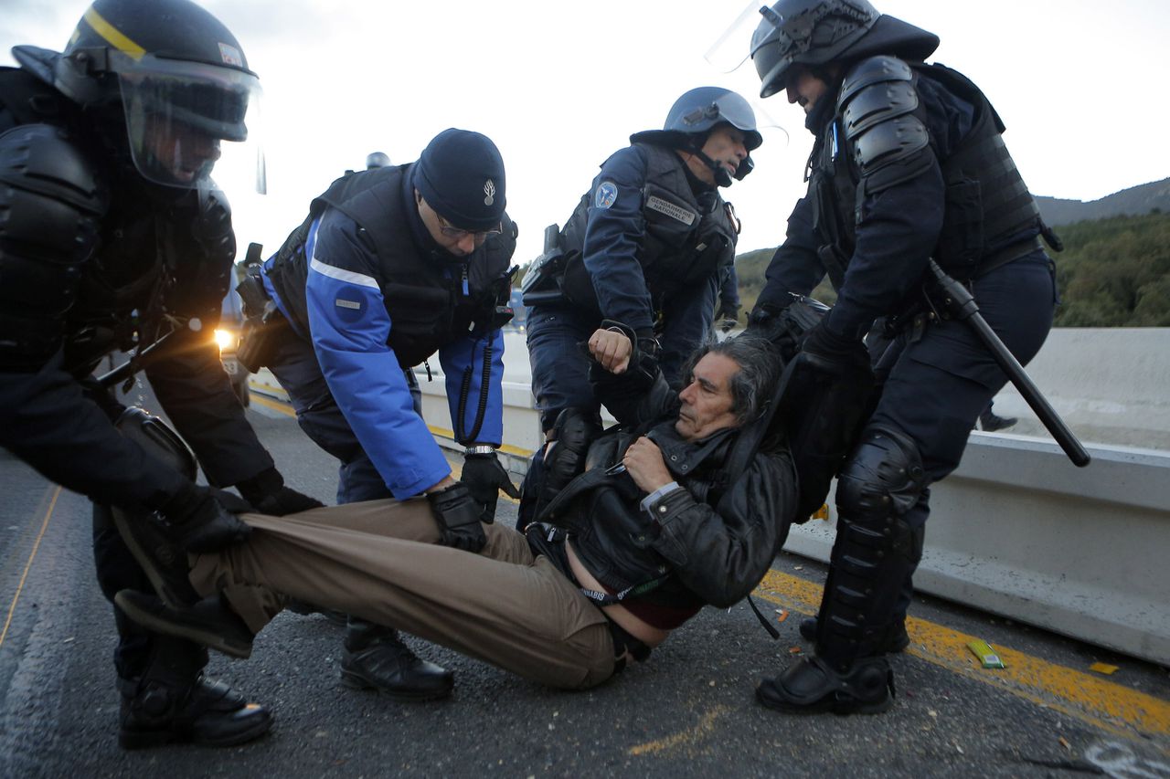 De Franse politie voert een demonstrant weg die de snelweg tussen Frankrijk en Spanje heeft geblokkeerd.