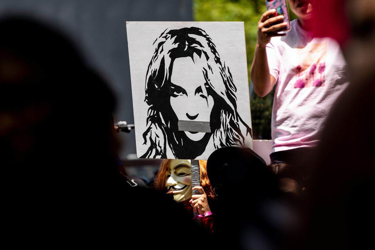 Demonstrant met een protestbord waarop een monddood gemaakte Britney Spears staat afgebeeld.