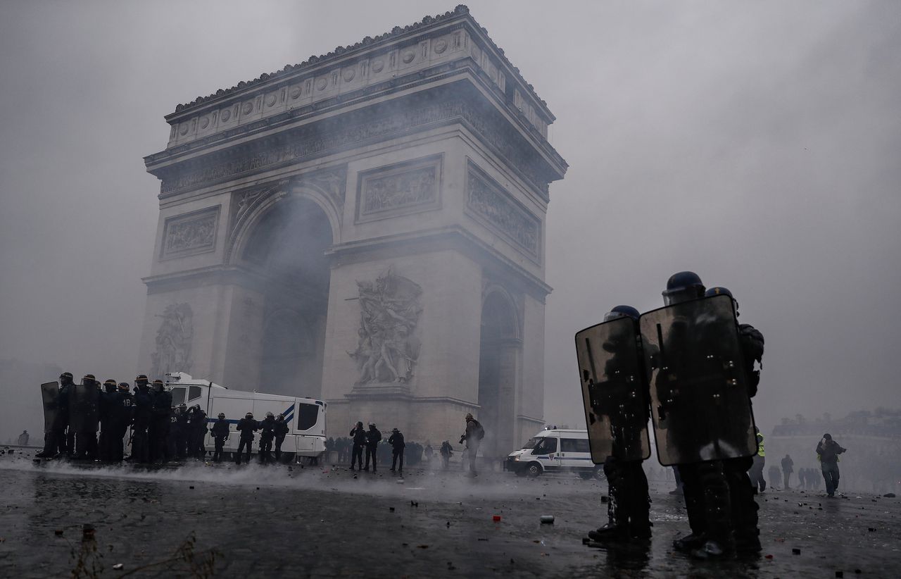 Oproerpolitie met waterkanon in wolken traangas tijdens rellen rond de Arc de Triomphe in Parijs op 1 december.